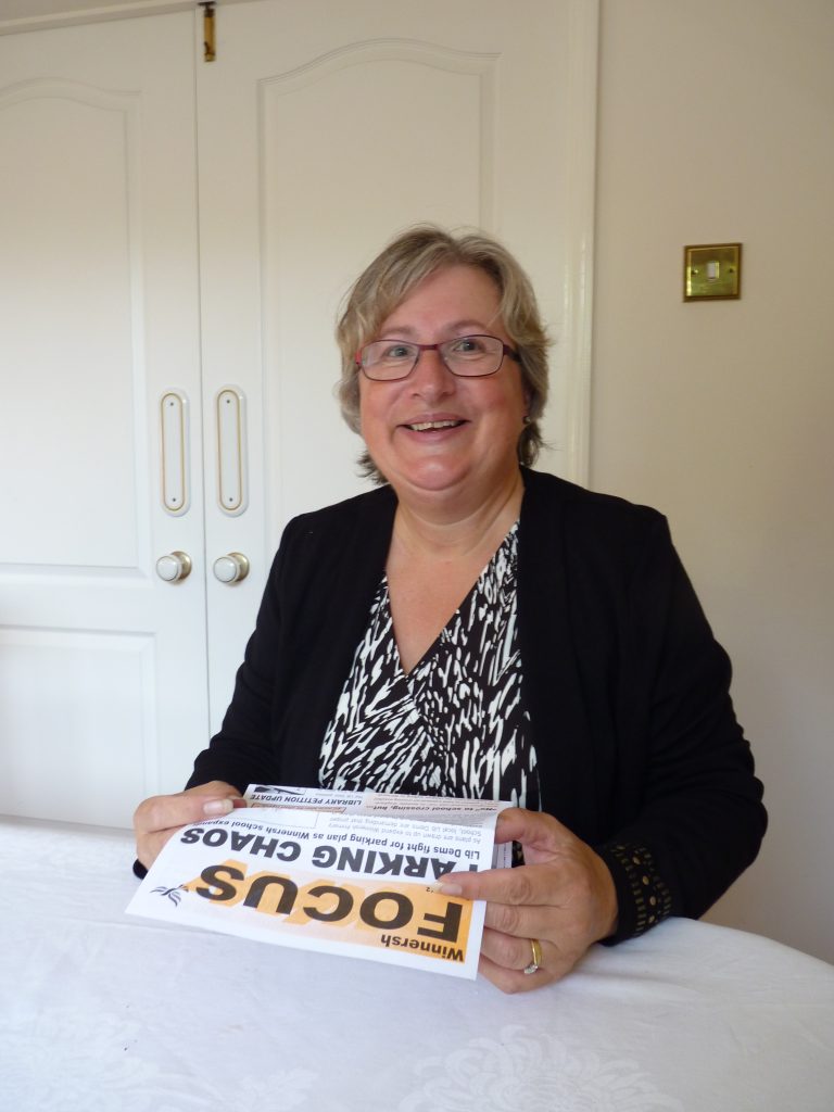 Prue Bray sitting at desk with bundle of Focus leaflets